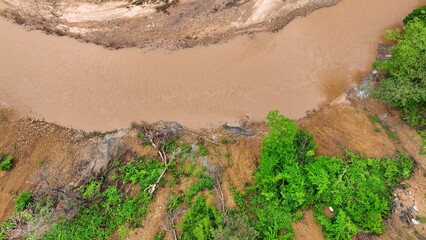 Aerial drone view of deforested slope and riverbank erosion after a landslide, emphasizing how climate change and global warming intensify natural hazards and landscape instability. Thailand.
