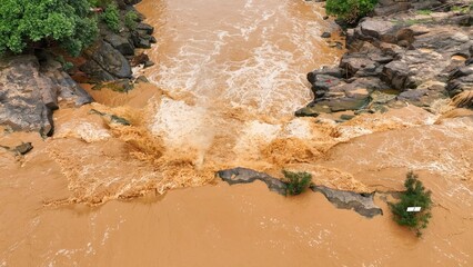 Overhead perspective reveals powerful floodwaters filled with sediment, showing how human-driven deforestation and soil degradation increase flood severity and landscape vulnerability. Thailand.
