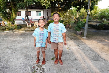 Two siblings in uniforms are going to school.