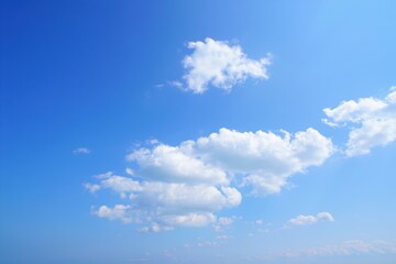 Bright blue sky with scattered white fluffy clouds on a clear sunny day conveying calm and peaceful atmosphere