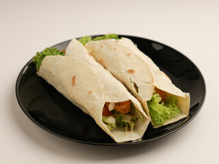 Tortilla with chicken salad filling on black plate