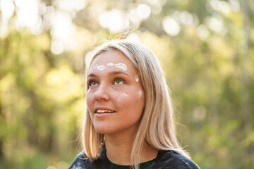 Young First Nations Australian woman looking up with upwards gaze and ochre paint on face