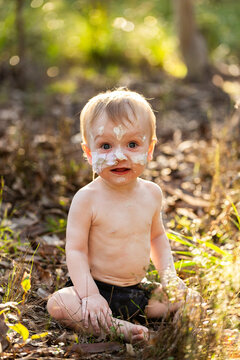 Portrait of aboriginal baby boy with ochre on face and feeding tube sitting in bushland