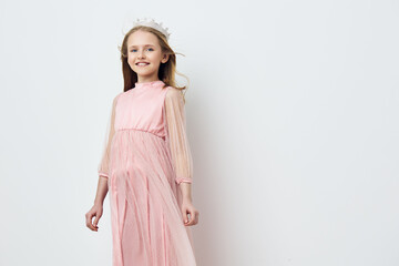 Young girl in a beautiful pink dress with transparent sleeves, wearing a floral crown and smiling...
