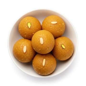 A white bowl filled with six besan laddu sweets garnished with nuts on top
