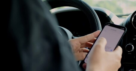 Close-up inside a car as the driver holds a smartphone near the steering wheel. The scene highlights technology use in vehicles, mobile distraction, risk, and modern commuting habits.