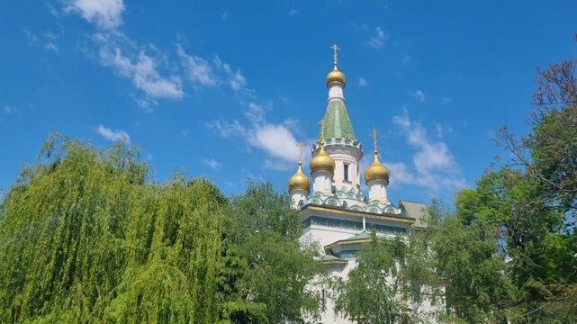 Golden domes and shining crosses of St. Nicholas the Miracle-Maker Church in Sofia, Bulgaria stand out against a vibrant blue spring sky, radiating serenity and light