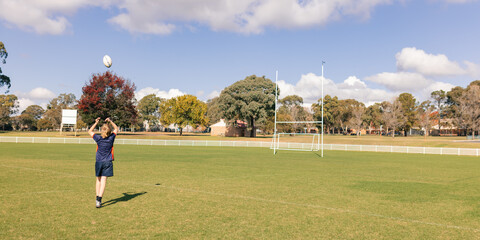 Teenage boy practicing ball handling skills on empty rugby field