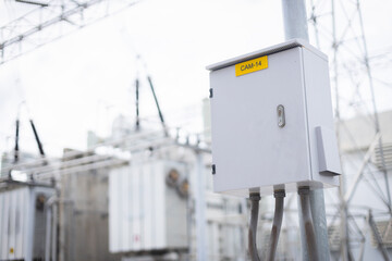 High voltage power substation infrastructure features control box mounted on pole with cables...