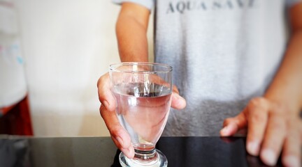 A man takes a glass of drinking water from the kitchen table. The concept of drinking needs.