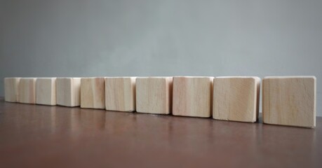 A row of plain wooden cubes extends across a wooden table. 