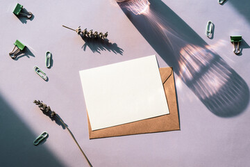 Minimalist flat lay composition with blank card, brown envelope, lavender and stationery in natural light. Top view, mockup