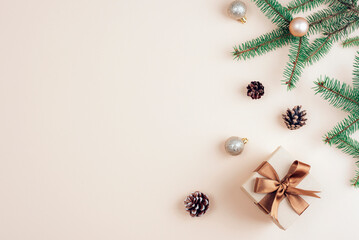 Christmas gift with brown ribbon and decorations on beige background. Top view, flat lay, copy space