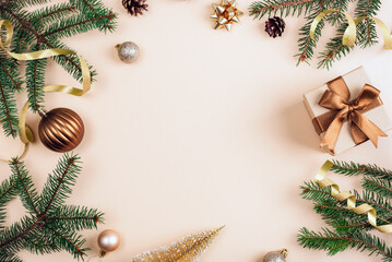Christmas composition with green pine branches, bronze gift boxes with ribbons and ornaments arranged on a beige background. Top view, flat lay, copy space