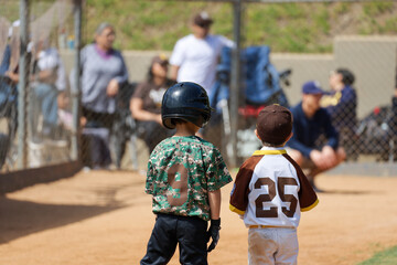 Back view of two little boys standing on first base during a baseball game.