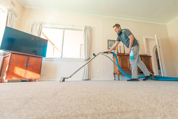 Male carpet cleaning professional using steam cleaner in home