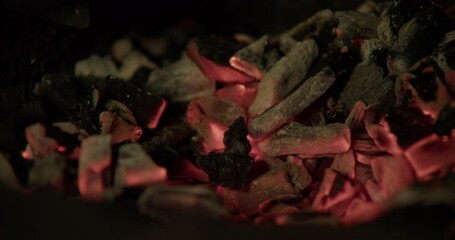 Static close-up of the blacksmith’s forge. The blacksmith uses a poking stick to stir the glowing coals.