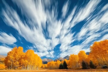 Fototapeta premium Timelapse of dynamic clouds shifting above vibrant autumn trees in a tranquil landscape, Time-lapse of clouds flowing in the blue sky