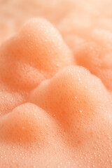 Fototapeta premium Abstract close-up of soft, peach-colored foam with glistening bubbles creating a fluffy, textured surface. Ideal for cosmetic or cleaning concepts.