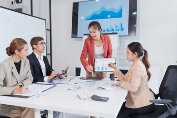 Group of Asian business people presenting their work on a board or on a tablet.