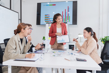 Group of Asian business people presenting their work on a board or on a tablet.