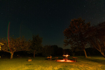 Fire pit burning brightly in rural Australian backyard at night under star lit sky