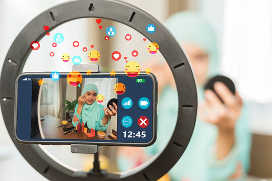 Muslim beauty influencer doing makeup tutorial livestream with smartphone, cosmetics, and social media icons