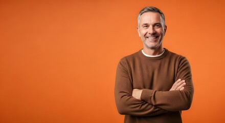 Fototapeta premium Portrait of handsome smiling man with arms crossed on orange background studio shot for stock photography