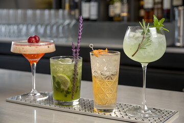 Four elegant cocktails on a bar tray
