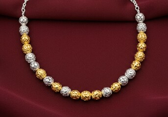 Obraz premium Elegant two tone gold and silver beaded necklace on red fabric