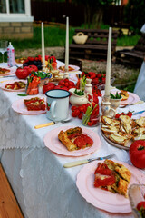 Beautiful romantic decor for a bachelorette party outdoors in the garden. The table is decorated with candles, tomatoes, flowers.