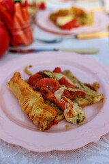 A slice of homemade pizza, with pesto and tomatoes, baked in a village oven.