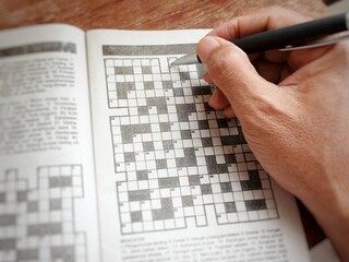 Leisure time activities. Someone fills in the blanks in a crossword puzzle.