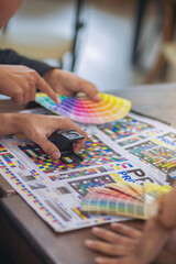 Team graphic designer checking print quality of media graphics proof print and color guides in...