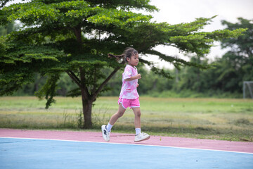 A young girl runs on a track in a park.