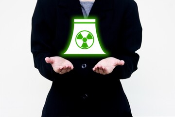 Nuclear power plant business concept with glowing green energy symbol held in hand. Ideal for clean...