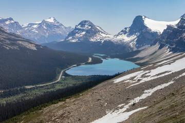 Breathtaking mountain landscape with tranquil lake under clear blue sky during summer near highway