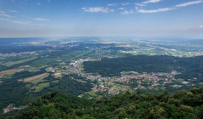 Drone panorama of the Ivrea Morainic Amphitheatre seen from Brosso, Val Chiusella, Italy, showing lush green plains, woods, and scattered villages under clear sky, high drone shot, slow motion
