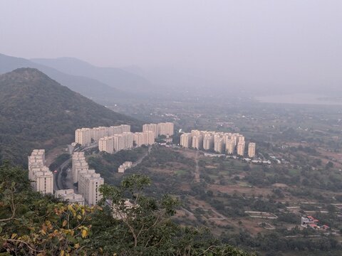 Distant cityscape view from lush green hilltop - Powered by Adobe