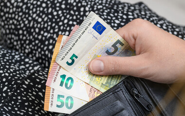 Kobieta wyjmuje z portfela pieniądze w walucie euro