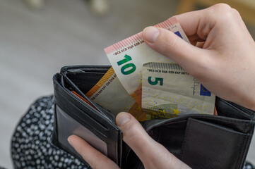 Studentka trzyma w dłoni portfel z banknotami euro