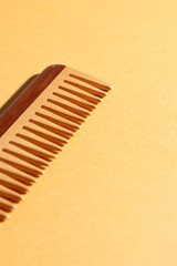 Close up of eco wooden comb at yellow background, show detail , copy space, hair care routine