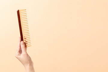 Hand holding Wooden Comb on white background with shadow simple image photo for beauty tools and market place