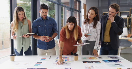 Team, creative business people and discussion with paper for brand strategist with tablet. Group, manager or collaboration in startup office for planning, brainstorming or idea for ad campaign design