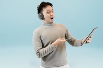Fototapeta premium man with headphone holding digital tablet in isolated blue background