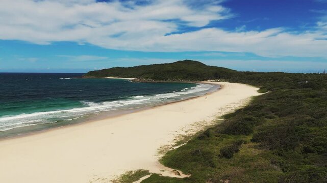 Sandy beach of Booti Booti National Park in New South Wales of Australia. Aerial rising wide shot. Turquoise ocean water and green mountains.