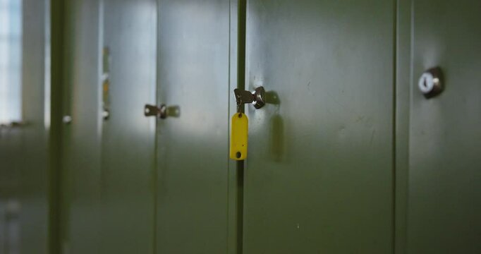 Slow camera dolly back past green lockers with key in focus &ndash; moody industrial setting