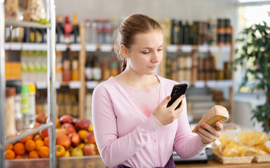 Young girl buyer scanning qr code for fresh cheese in grocery store
