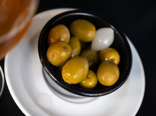 Delicious large green olives with pits served on a platter with onions