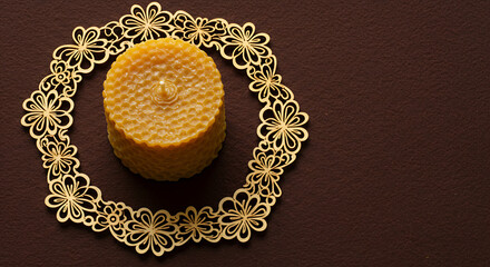 Round beeswax candle placed on intricate golden lace coaster  